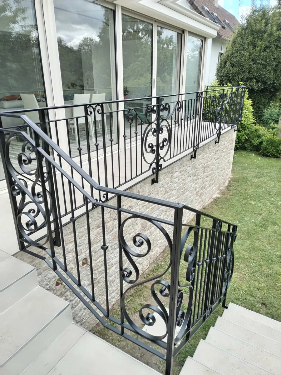 Garde-corps de terrasse extérieur en fer forgé noir à volutes, devant une maison côté jardin, L'Art de Faire